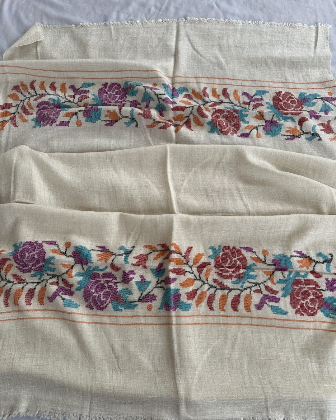 The soft ivory base is beautifully complemented by vibrant floral motifs, creating a timeless accessory that blends sophistication with cultural authenticity. Lightweight, warm, and exceptionally soft, this shawl is perfect for formal occasions, festive gatherings, or everyday luxury.
